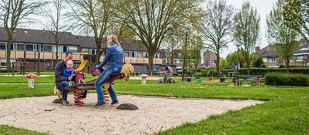 foto van ouders spelend met kind in speeltuin