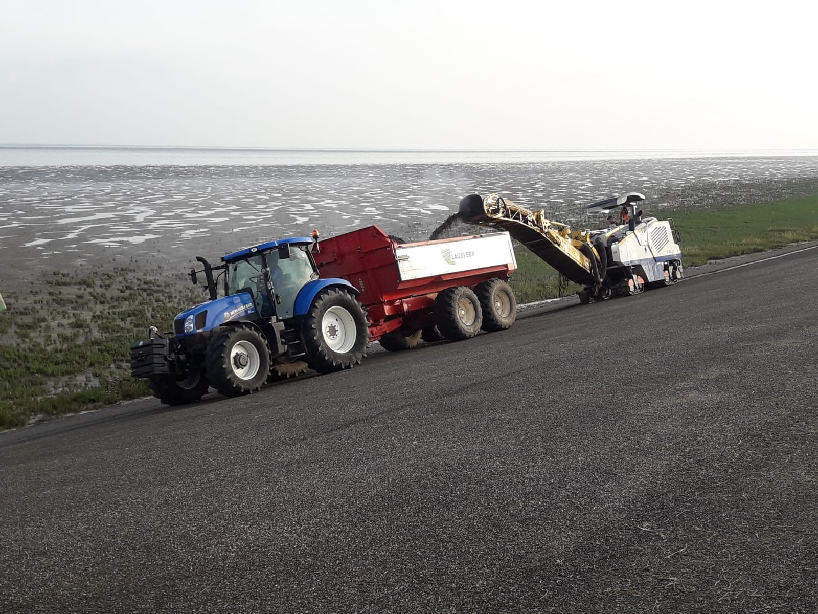 Op deze afbeelding staat een asfaltfees en dumper.